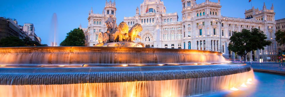 Bildet fremviser en storslått fontene foran en imponerende bygning i skumring.
