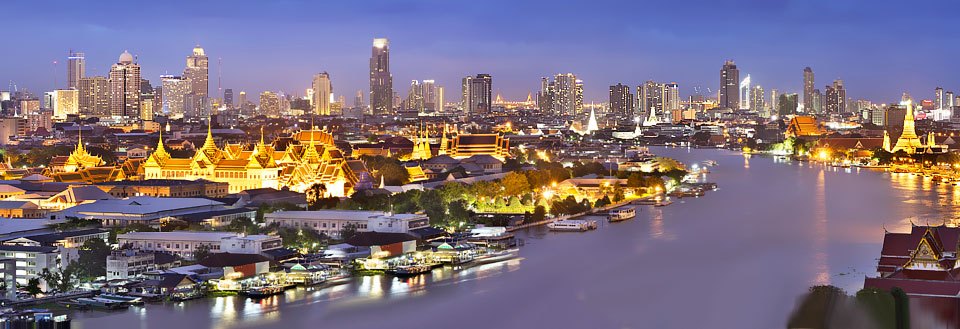 Panoramautsikt over en Bangkok om kvelden med belyste bygninger og Chao Praya-elven som renner gjennom byen.