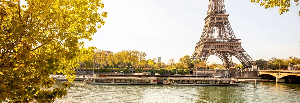 Eiffeltårnet i Paris, Frankrike, med en sightseeingbåt på Seine-elven og gyldne høstløv.