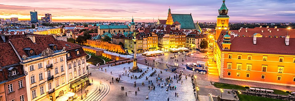 Bildet fremstiller en livlig torg i Warszawa  i skumringen, omkranset av historiske bygninger og spaserende mennesker.