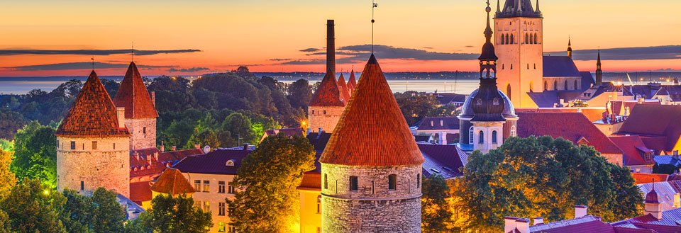 Kveldsbilde av Tallinn med tårn og spir mot en solnedgangsbakgrunn.