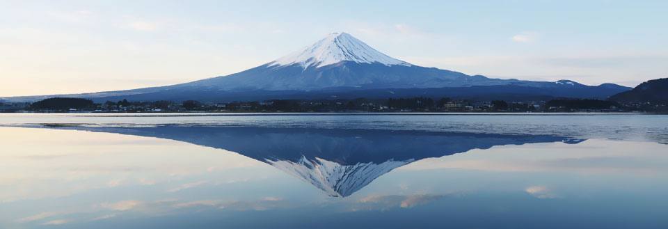 Bildet viser det snødekte Mount Fuji speilet i vann under skumring.