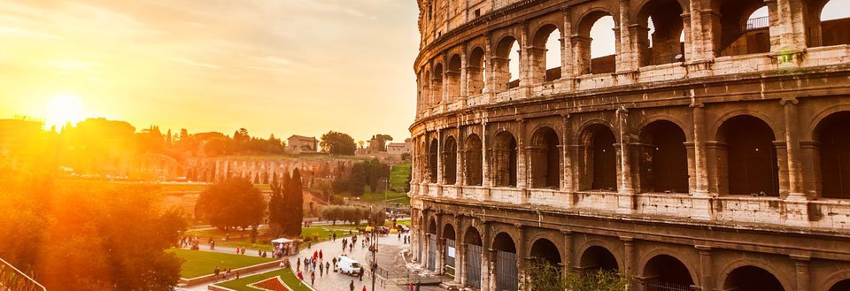 Colosseum i Roma ved solnedgang med folk som går rundt.