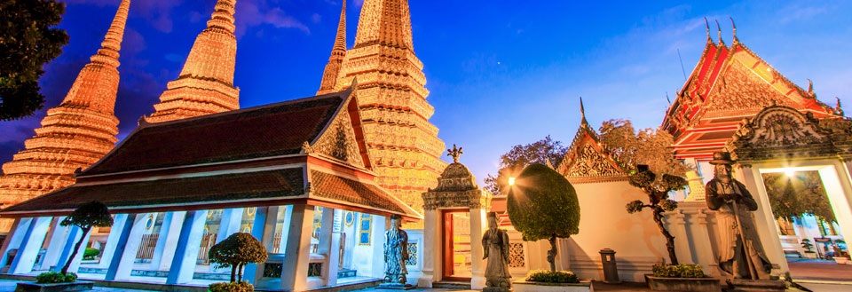 Wat Pho-tempelet i Bangkok i skumringen med belyste chedis (stupaer) og dekorerte paviljonger.